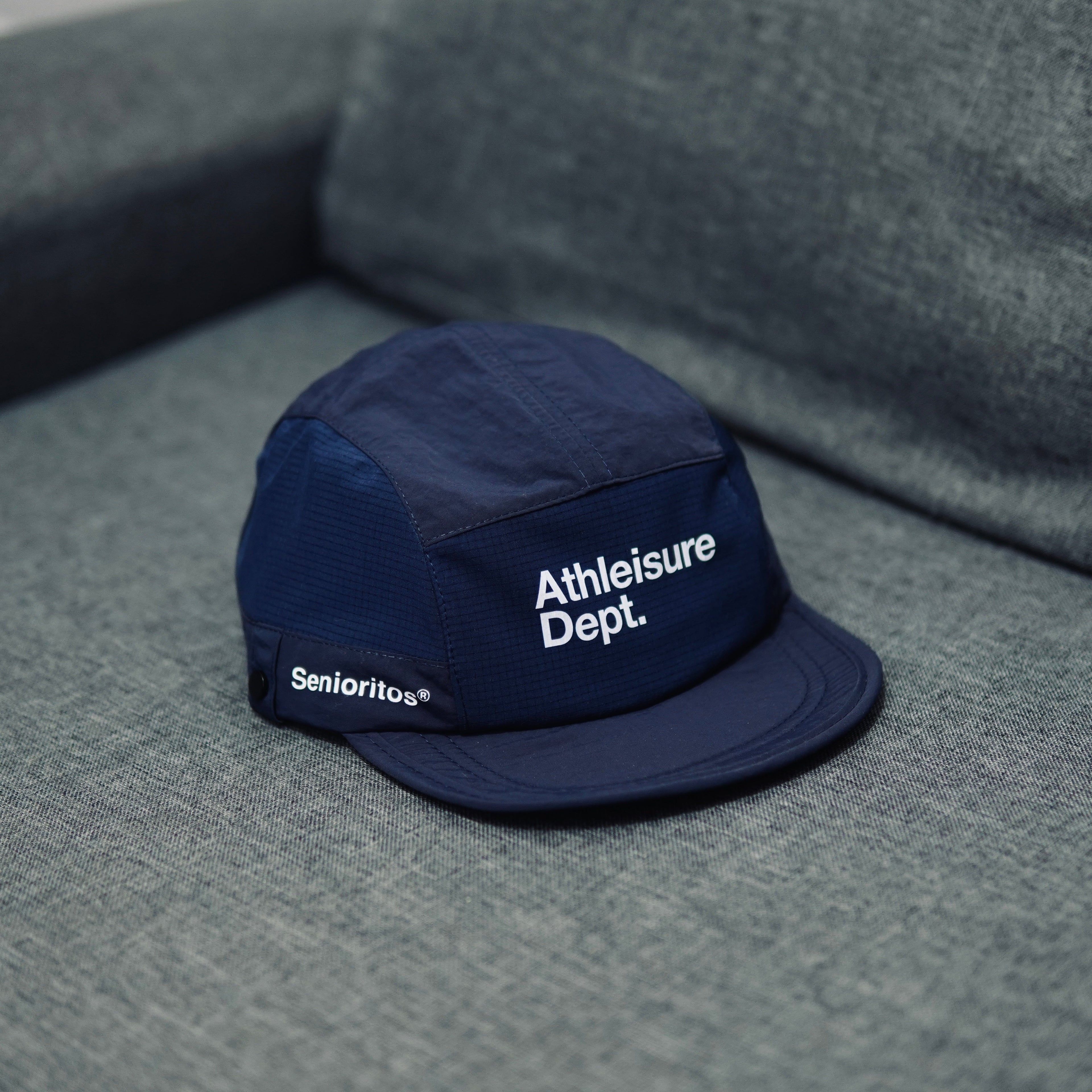 Navy cap with 'Athleisure Dept.' text on a gray surface